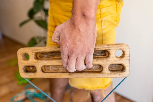 strong male hand of a rock climber holds a board for training finger strength. climbing workout at home. rock climber\'s hand close-up. strength and endurance. fingerboard and hangboard