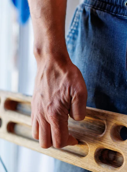 strong male hand of a rock climber holds a board for training finger strength. climbing workout. rock climber's hand close-up. strength and endurance. fingerboard and hangboard. extreme sport