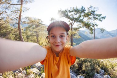 Tatlı bir çocuk cep telefonuyla selfie çekiyor. Dağlara yolculuk.