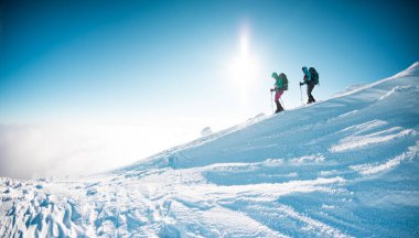 two girls walk along a mountain path in snowshoes. walking in the snow. hiking in the mountains in winter.