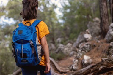 Macera ve seyahat. Sırt çantalı bir çocuk orman yolunda duruyor. Çocuklarla geziler. Ormandaki çocuk.