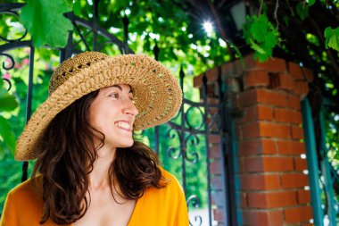 Hasır şapkalı mutlu bir esmerin portresi. Kız gülümsüyor ve tatilin tadını çıkarıyor. Yakın plan..