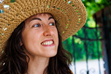 Hasır şapkalı mutlu bir esmerin portresi. Kız gülümsüyor ve tatilin tadını çıkarıyor. Yakın plan..