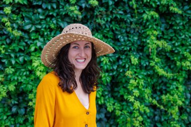 Hasır şapkalı mutlu bir esmerin portresi. Kız gülümsüyor ve tatilin tadını çıkarıyor. Yakın plan..