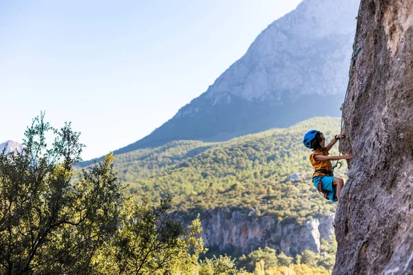 子供用ロッククライミング 少年は山を背景に岩に登る 趣味は 運動能力のある子供は強くなるように訓練する 安全登山 — ストック写真