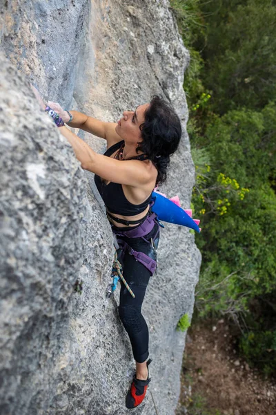 stock image Rock climber girl climbing a rock with a dinosaur tailA woman climbs the rock. Training on natural terrain. Extreme sport. The climber trains on a natural relief. 