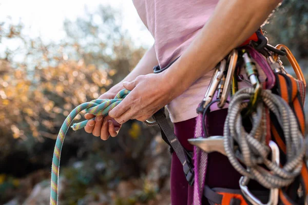 登る前に結び目を結ぶクライマー ハーネスや登山機器のロッククライマーのクローズアップ屋外 — ストック写真