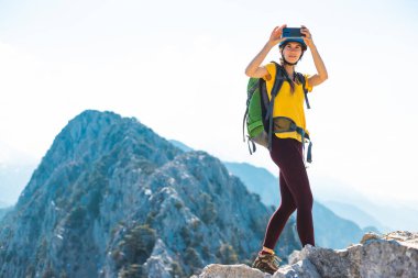 Dağın tepesindeki dağcı fotoğraf çekiyor. Kadın gezgin modern bir akıllı telefondan fotoğraf çeker, güzel dağ manzaralarının güzel resimlerini çeker. dağ tırmanışı ve macera.
