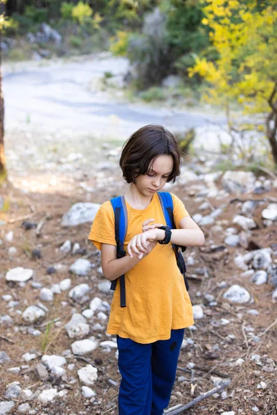아이는 등산중에 손목시계를 배낭을 시계를 들여다보고 — 스톡 사진