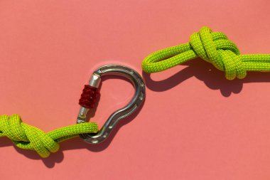 İple çizilmiş karabina renkli bir arka planda yatıyor. Tırmanma ve dağcılık ekipmanları. Güvenlik halatı. Güvenilirlik ve güç kavramı. Boşluğu kopyala.