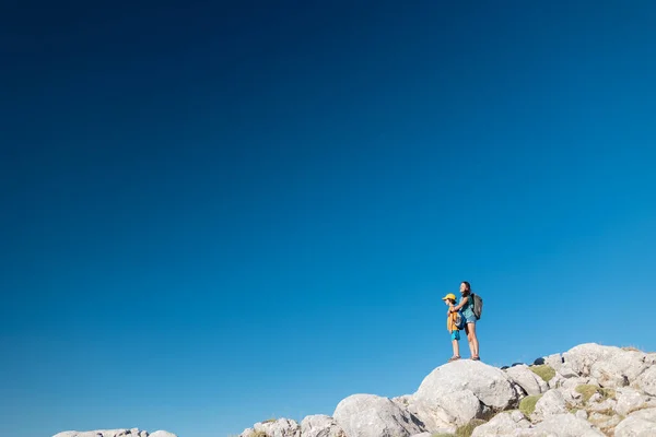 stock image The boy and his mother are standing on the top of the mountain, A woman is traveling with child, Boy with his mother looking at the mountains, Travel with backpacks, Hike and climb with kids