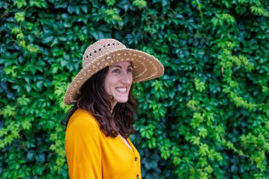 Şapkalı ve sarı elbiseli genç ve güzel bir kız kameraya gülümsüyor. Yakın plan. Tatildeki mutlu kız..