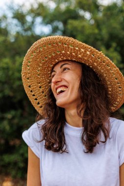 Hasır şapkalı mutlu bir esmerin portresi. Kız gülümsüyor ve tatilin tadını çıkarıyor. Yakın plan..