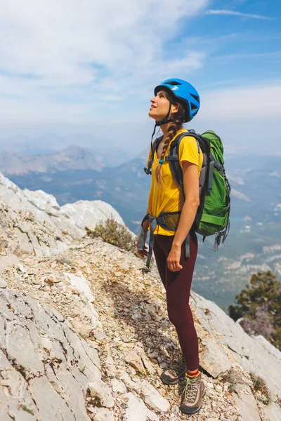 山の頂上にはリュックとヘルメットが立っています 女の子は山の中で登る 冒険と登山の概念 山の中でバックパックを持ってハイキングをし — ストック写真
