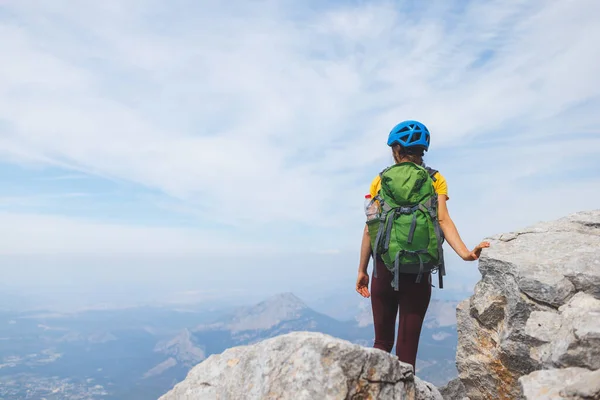 山の頂上にはリュックとヘルメットが立っています 女の子は山の中で登る 冒険と登山の概念 山の中でバックパックを持ってハイキングをし — ストック写真