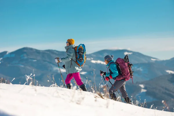 游客们一起在山上旅行 两个被雪覆盖的高山女孩 穿着雪鞋在山上远足 — 图库照片