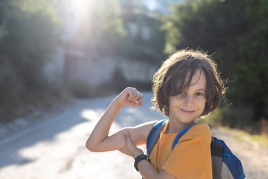 Çocuk kol kaslarını ve gülümsemelerini gösteriyor. Mutlu çocuk eğleniyor..