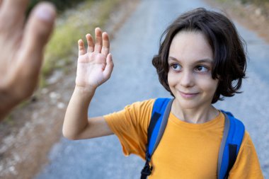 Sırt çantalı çocuk beş veriyor. Çocuk ebeveynleriyle vakit geçirmekten hoşlanıyor. Ormanda çocuk yürüyüşü ve macera..