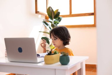 Çocuk evde video öğretmeniyle, evde, evde, uzaktan öğrenme, çevrimiçi eğitim, çevrimiçi ders alan çocuk, uzaklık eğitimi ve internet üzerinden öğrenim görüyor.