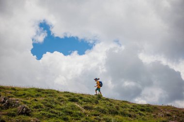 Çocuk sırt çantasıyla dağlardaki bulutların arkasına gidiyor. Sırt çantalı çocuk gezgini, yürüyüş, seyahat, yaşam tarzı konsepti