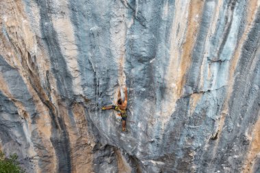 Kaya tırmanışçısı kayaya tırmanır. Güçlü bir adam zor bir yolun üstesinden gelir. Rahatlama ve doğada özgürlük.