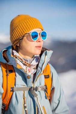 Bir kadın karda kar ayakkabılarıyla yürür, kış yürüyüşü yapar, kışın dağlarda yürüyüş malzemesi taşır.