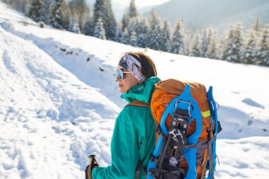 Sırt çantasında kar ayakkabıları, kış yürüyüşü, kışın dağlarda yürüyüş ekipmanları olan bir kadın.