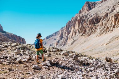 Sırt çantalı çocuk dağ yolunda yürüyor. Çocuk bir sırt çantasıyla dağlara seyahat ediyor. Yüksek dağlarda dağ yürüyüşü. Türkiye.