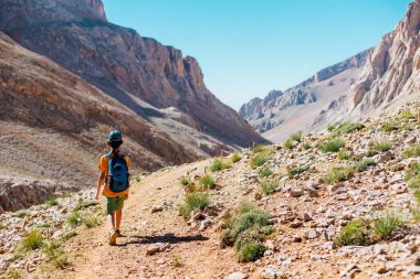 Sırt çantalı çocuk dağ yolunda yürüyor. Çocuk bir sırt çantasıyla dağlara seyahat ediyor. Yüksek dağlarda dağ yürüyüşü. Türkiye.