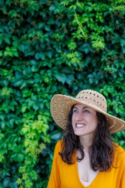 Şapkalı ve sarı elbiseli genç ve güzel bir kız kameraya gülümsüyor. Yakın plan. Tatildeki mutlu kız..