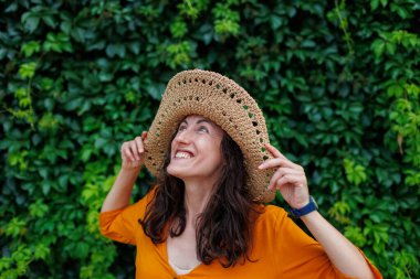 Hasır şapkalı mutlu bir esmerin portresi. Kız gülümsüyor ve tatilin tadını çıkarıyor. Yakın plan..