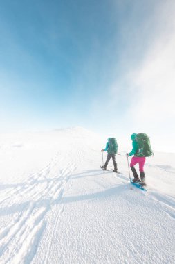 Kış dağlarında kar ayakkabılı iki turist. Dağlarda macera..