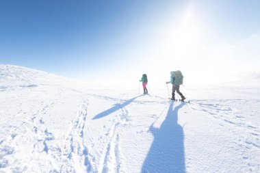 two girls walk along a mountain path in snowshoes. walking in the snow. hiking in the mountains in winter.