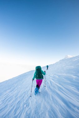 İki dağcı dağa tırmanır. İki kız karla kaplı bir dağa tırmanıyor. Kış dağcılığı.