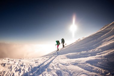 Turistler kışın dağlarda birlikte seyahat ederler. İki kız, karla kaplı dağlar. Dağlarda kar ayakkabılarıyla yürüyüş yapmak.