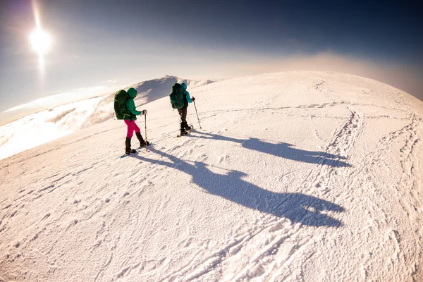 two tourists in the winter mountains on snowshoes. Adventure in the mountains.