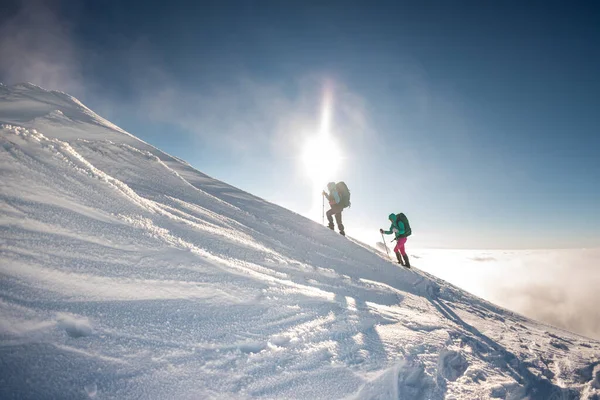 two climbers climb the mountain. Two girls climb a snow-covered mountain. winter mountaineering.