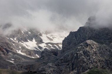 Türkiye 'nin arka planında karlı dağlarla kaplı bir arazinin üzerinden geçen bulutlar. Dağların ve sıradağların manzarası. Türkiye 'de dağcılık. Dedegol. Türkiye.