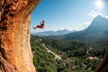 Kaya tırmanışçısı yoldan iniyor, dağcı bir ipe tutunuyor, kemer şeklinde bir kaya, mağaradaki tırmanma rotaları, bir kız ip üzerinde gidiyor.