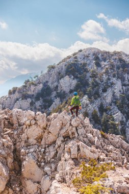 Sırt çantalı ve kasklı bir dağcı dağdaki bir dağ yolu boyunca gider. Dağlarda tırmanan bir kız. macera ve dağcılık konsepti. Dağlarda bir sırt çantasıyla yürüyüş..
