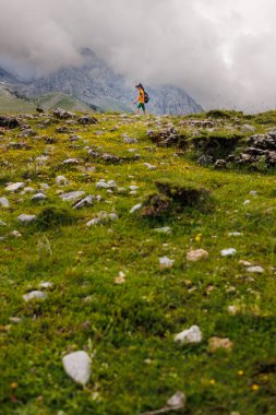 Sırt çantalı bir çocuk dağların arka planında yürüyüş yapıyor. Sırt çantalı çocuk gezgini, yürüyüş, seyahat, yaşam tarzı konsepti, arka planda dağlar, yaz tatili çocukları..