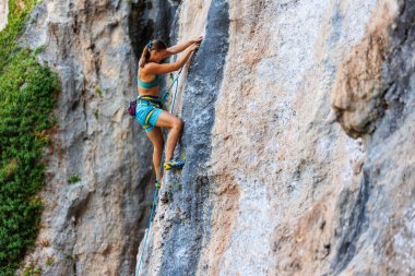 Genç ve güçlü bir kadın kayaya tırmanıyor. Güç ve dayanıklılık.