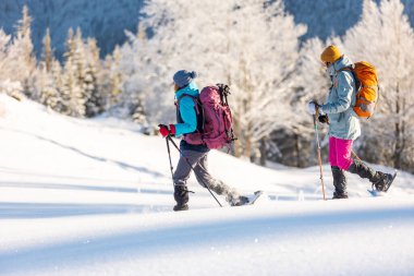 Kış dağları. Kar ayakkabılı ve sırt çantalı iki kişi yürüyüşe çıktı. Macera ve aşırı eğlence kavramı..