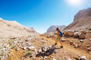 Çocuk sırt çantasıyla dağlarda geziyor. Yüksek dağlarda dağ yürüyüşü. Çocuk bir dağ yolunda yürüyor. Türkiye.