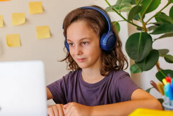 child listens to music at the lesson. Boy with curly hair is happy with distance learning. Lessons take place over the Internet.