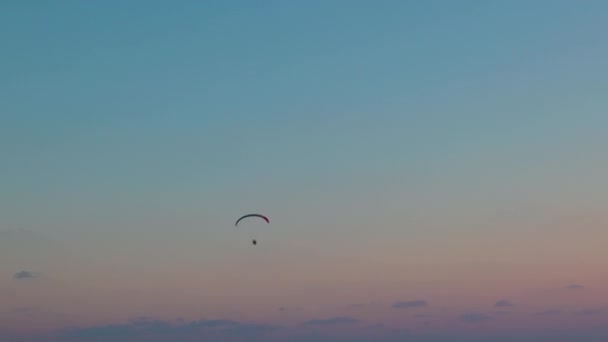 一つのパラグライダーは 雲と日没の背景に対して空を飛ぶ 空のパラグライダー — ストック動画