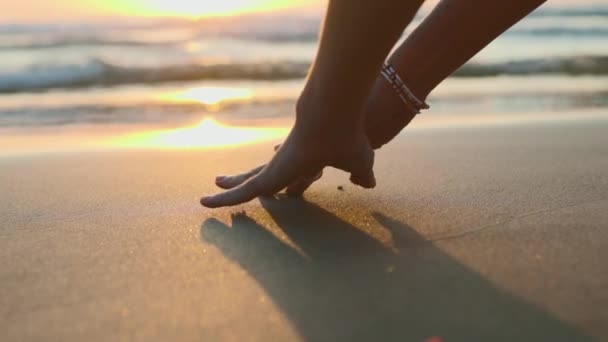 Девушка Рисует Пальцами Мокрому Песку Руки Вверх Рисунки Песке Закат — стоковое видео