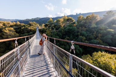 Şapkalı genç kız asma köprüde duruyor ve hayallerindeki uzaklığa bakıyor. yakın plan.