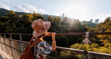 Şapkalı genç kız asma köprüde duruyor ve hayallerindeki uzaklığa bakıyor. yakın plan.
