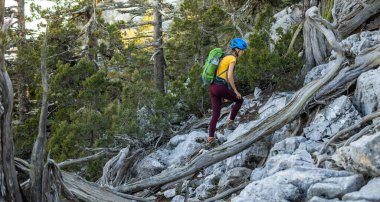 Sırt çantası ve dağlarda miğferi olan bir kadın tırmanıcı. macera ve dağcılık konsepti. Dağlarda bir sırt çantasıyla yürüyüş yapmak. Türkiye dağları.